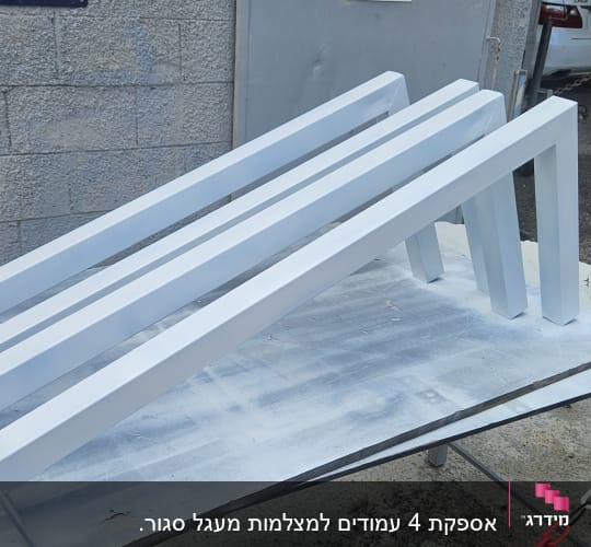 מסגרות מתכת לבנות מונחות על שולחן עבודה